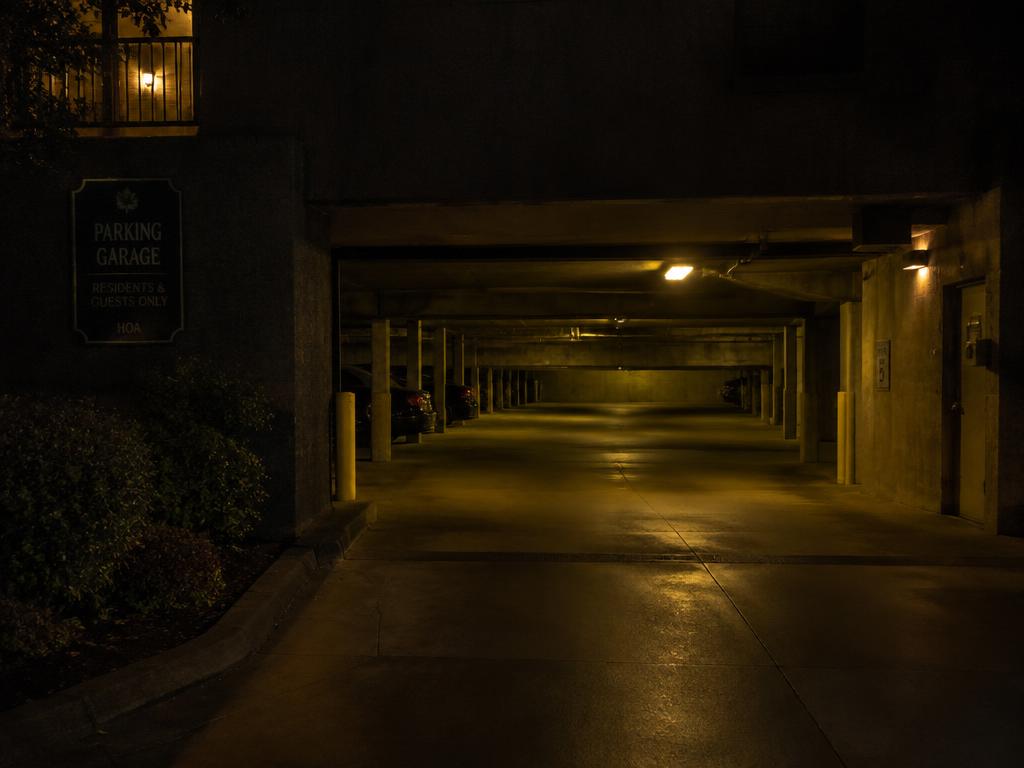 Dark HOA parking garage entrance lit by dim yellow fixtures